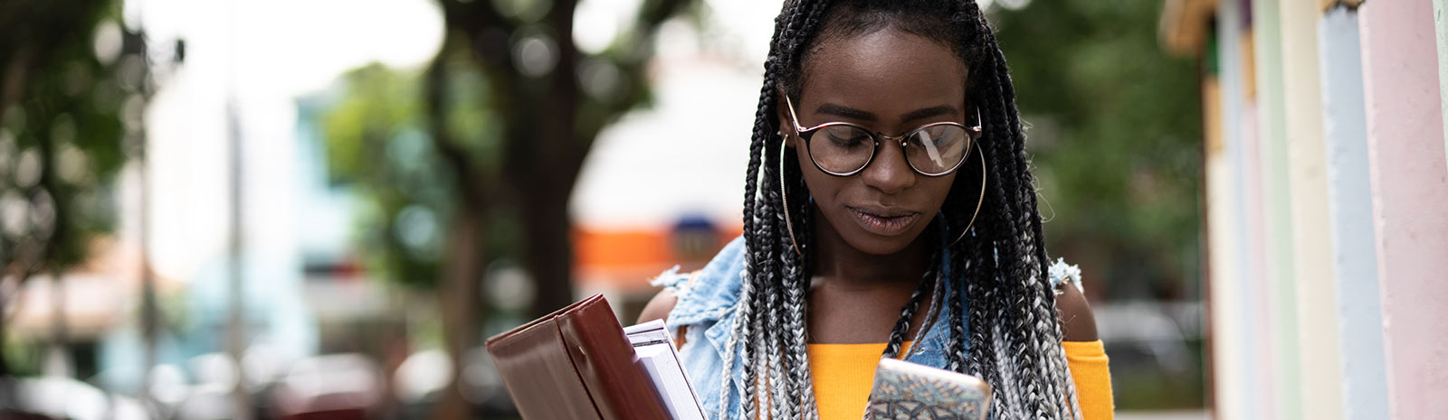 woman using mobile device and holding books