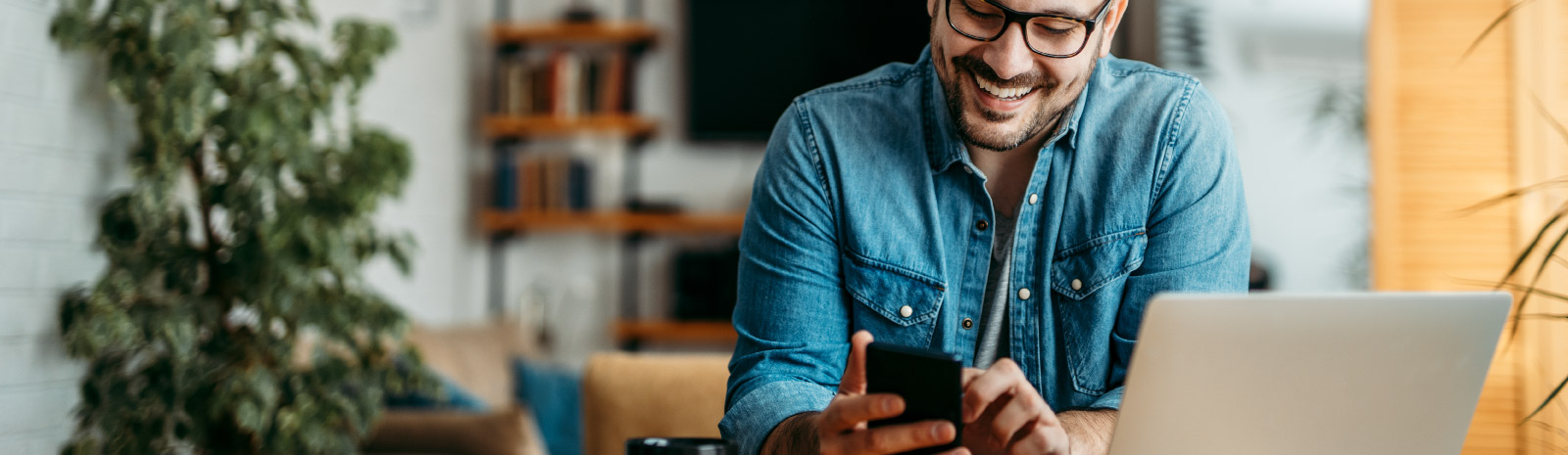 man using a mobile device and laptop