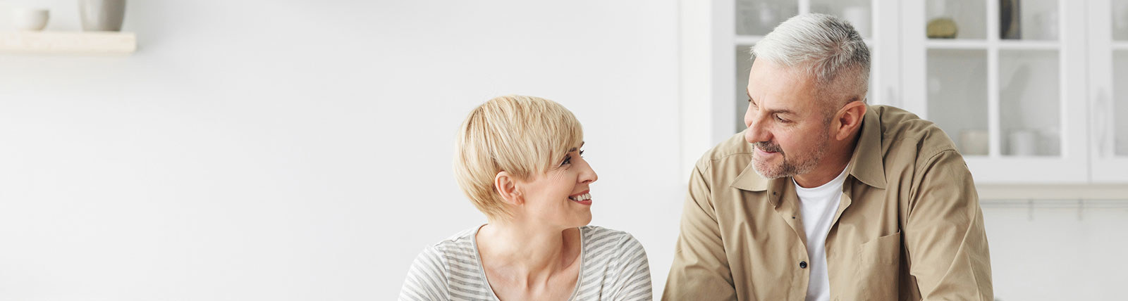 Mature couple smiling at each other in kitchen